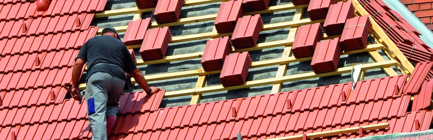 Unser erfahrener Mitarbeiter arbeitet auf einem Dach in Lüneburg. Präzision und Fachkenntnisse in jeder Dachsanierung und Bauaufgabe.